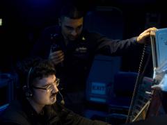 Two U.S. Navy operations specialists stand watch aboard the USS Dwight D. Eisenhower. The Navy must provide cybersecurity for major systems aboard ships as well as for smaller logistical systems, all of which are targets for digital adversaries. U.S. Navy photo