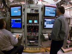 Technicians test systems in the Space and Naval Warfare Systems Center Atlantic's Common Submarine Radio Room (CSRR) production area. The curved design of the facility mimics the hull designs of four Navy submarine types, which allows for streamlined integration before systems are installed aboard the subs, and reduces cost and installation time.