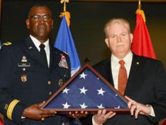 Maj. Gen. Cedric Wins, USA, commander of U.S. Army Research, Development and Engineering Command, presents a flag to Henry Muller Jr., who has retired as director of the Communications-Electronics Research, Development and Engineering Center after a nearly 33-year federal career. Donald Reago Jr. is serving as acting director.