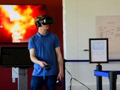 Jack Lewis, a NIST associate, demonstrates the use of a virtual reality headset and controllers with NIST’s virtual office environment in which first responders search for a body in a fire. Credit: Burrus/NIST