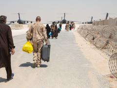 Master Sgt. Michael Lesterick, USMC, carries an Afghan evacuee’s luggage as they board a plane at Al Udeid Air Base, Qatar, September 1, 2021. The Department of Defense, including its combatant commands, such as the U.S. Transportation Command, is still supporting the evacuation of American citizens, special immigrant visa applicants and other at-risk individuals from Afghanistan. Credit: U.S. Marine Corps photo by Lance Cpl. Kyle Jia