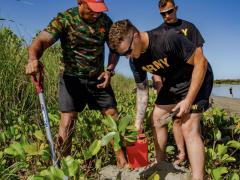 Two U.S. Army specialists join a Fijian Army sergeant in planting Dilo trees as part of a coastal and reef revitalization project in the Republic of Fiji. The U.S. Army works with local officials domestically and overseas in projects to support environmental concerns to avoid or repair damage.