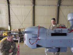 Two U.S. Navy officers inspect an MQ-5B Hunter unmanned aerial vehicle (UAV) at Kandahar Airfield in Afghanistan. The Navy’s increased use of UAVs is changing the nature of its air operations, but it also is raising concerns about manned versus unmanned missions.