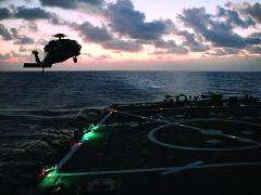 An H-60S helicopter conducts deck landing qualifications on USS Milius destroyer off the coast of Guam. Milius was the first ship to begin installing CANES and will serve as the operational testing platform for the next-generation afloat network.