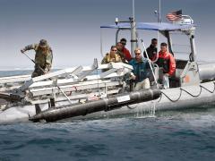 SPAWAR Systems Center Pacific personnel and sailors from Explosive Ordnance Disposal Mobile Unit ONE retrieve an unmanned underwater vehicle deployed to detect mines and improvised explosives in shallow water environments.
