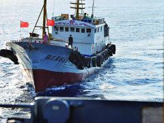 A crewmember aboard a Chinese trawler tries to snag the towed acoustic array of a U.S. Navy ocean surveillance ship in international waters in the South China Sea.