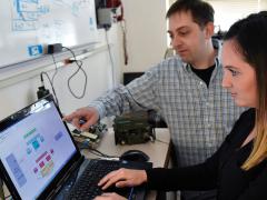 Aaron Cohen, computer engineer and electrical engineer at the U.S. Naval Research Laboratory, discusses radio frequency relay testing with Amanda Bowling. To improve long-range communications, researchers at the lab developed a method to combine multiple weak signals into one stronger signal. Credit: NRL