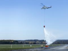 The unmanned version of Kaman Corporation’s K-MAX platform demonstrates dropping water on a controlled fire during trials at Griffiss Air Force Base in New York.