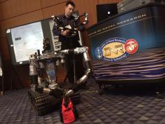 Aaron Nicely, of RE2, manipulates the High Dexterity Robot to retrieve candy from a bag at the Naval Future Force Science and Technology Expo.