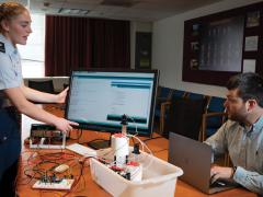 Hollis Roush, a Coast Guard Cadet intern at the Massachusetts Institute of Technology Lincoln Laboratories (MITLL), demonstrates a prototype representative industrial control system. Credit: Glen Cooper, MIT Lincoln Laboratory