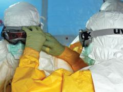 Health care providers adjust personal protective equipment as they prepare to enter a facility treating the Ebola virus in Liberia. Future pandemics could come from natural viruses or biological weapons developed by sophisticated nations; but whichever the source, opportunistic foes will take advantage of their effects to wreak further havoc on victim nations. (U.S. Army photo)