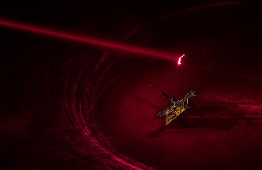 To power RoboFly, engineers pointed an invisible laser beam, shown here as a red laser, at a photovoltaic cell, which is attached above the robot and converts the laser light into electricity. Credit: Mark Stone/University of Washington