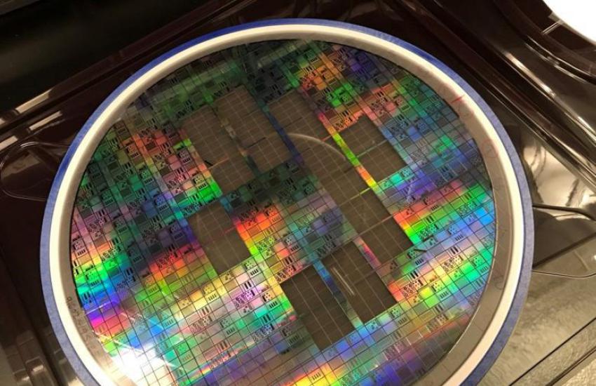 A 300 mm photonic integrated circuit semiconductor wafer developed by the U.S. Naval Research Laboratory Optical Sciences Division is patterned into 64 identical parts, each one called a reticle. Twenty reticles have been removed from the wafer for photonic test and analysis with functionalities targeting Department of Defense priorities such as quantum information and computing. Credit: U.S. Naval Research Laboratory
