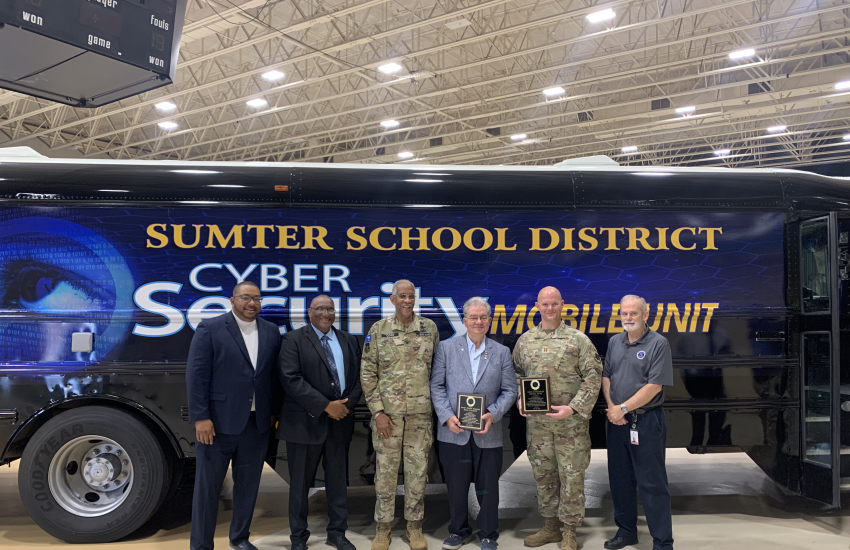 The team responsible for the STEM Bus initiative poses for a photo with the finished product, which will affect future generations of cyber warriors.
