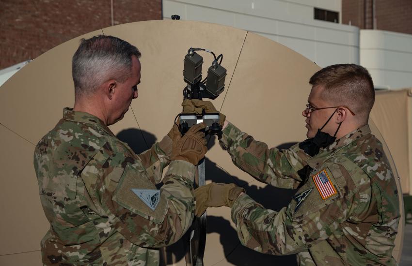 U.S. Space Force Tech. Sgt. John Idleman (r), 16th Space Control Squadron Mission Assurance Engineering section chief, demonstrates a Gigasat FA-150 antenna for Lt. Gen. Stephen Whiting, Space Operations commander, at Peterson Space Force Base, Colorado, in December 2021. Having maintenance and acquisition personnel, along with cyber and intelligence professionals integrated with operators around a specific mission area closes communications gaps, leaders say. Credit U.S. Space Force photo by Airman 1st Cla