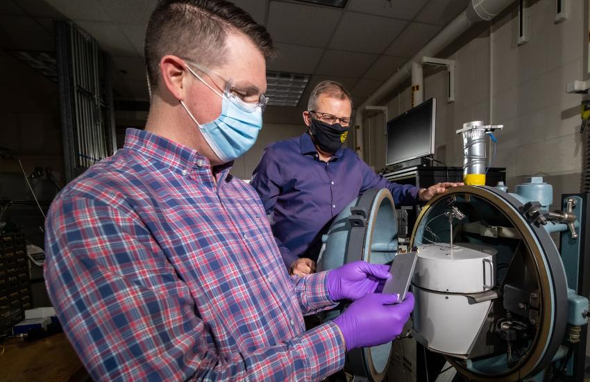 Sandia National Laboratories engineers examine a lithium-ion battery in front of a specially designed battery testing chamber. Credit: Flickr image by U.S. Department of Energy