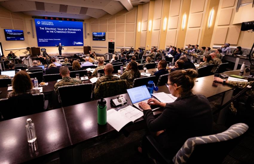 The defense industrial base must do more to shore up its cybersecurity, says Gen. Timothy Haugh, USAF, commander U.S. Cyber Command; director of the National Security Agency (NSA) and chief of the Central Security Service., pictured speaking at the U.S. Cyber Command Legal Conference at Joint Base Andrews, Maryland in April. Credit: U.S. Cyber Command Sklyer Wilson.