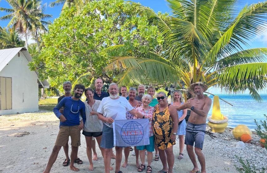 Jüri Grigorjev showcases the AFCEA flag on the Toau Atoll with friends he met along his two-year sailing trip.