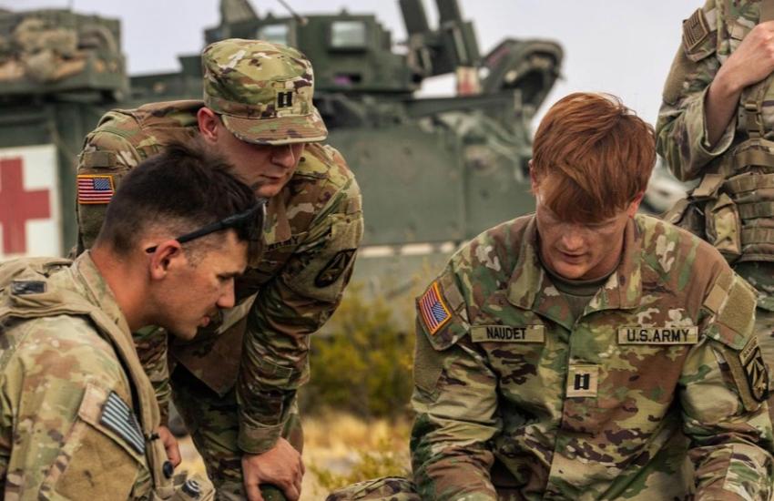 U.S. Army Cpl. Michael Hurst, assigned to 5th Squadron, 7th Cavalry Regiment, 1st Armored Brigade Combat Team, 3rd Infantry Division (l), Capt. Thomas Canchola and Capt. Timothy Naudet, both assigned to the Artificial Intelligence Integration Center, Army Futures Command, discuss how to use a Tethered Unmanned Aircraft System with Sentinel Software at the National Training Center, Fort Irwin, California, July 2024. Credit: U.S. Army photo by Spc. Rebeca Soria