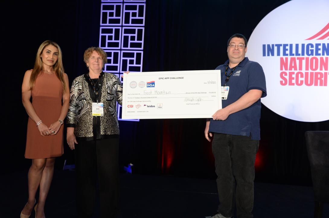 Chair of AFCEA’s EPIC Committee, Niloo Norton, (l) and Director of the Commercial Innovation Center of Riverside Research, Ann Carbonell, (c) present a $13,000 check to David Vigna, founder of Frost Mountain and winner of EPIC Challenge 2022 at the Intelligence & National Security Summit. 