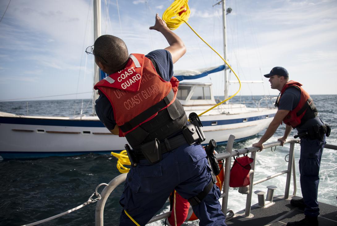 Coast Guardsman throws a rope across to a stranded sailor during a rescue in the Gulf of Mexico. Photo By: U.S. Air Force photo, 2nd Lt. Karissa Rodriguez.