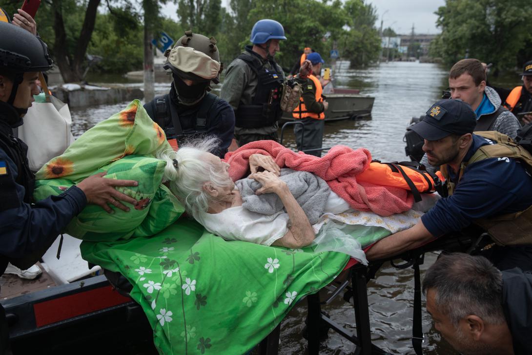 Lifeguards and volunteers evacuate an elderly woman in Kherson, Ukraine, after the Kakhovka Dam was allegedly destroyed by Russian occupying forces in June, causing floods. Credit: Drop of Light/Shutterstock