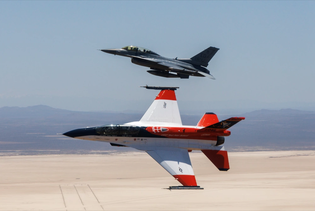 Secretary of the U.S. Air Force Frank Kendall flies in the X-62 VISTA in the skies above Edwards Air Force Base, California, on May 2, 2024. Cubic Defense’s SLATE pods are seen on both aircraft. Credit: Air Force photo by Richard Gonzales.