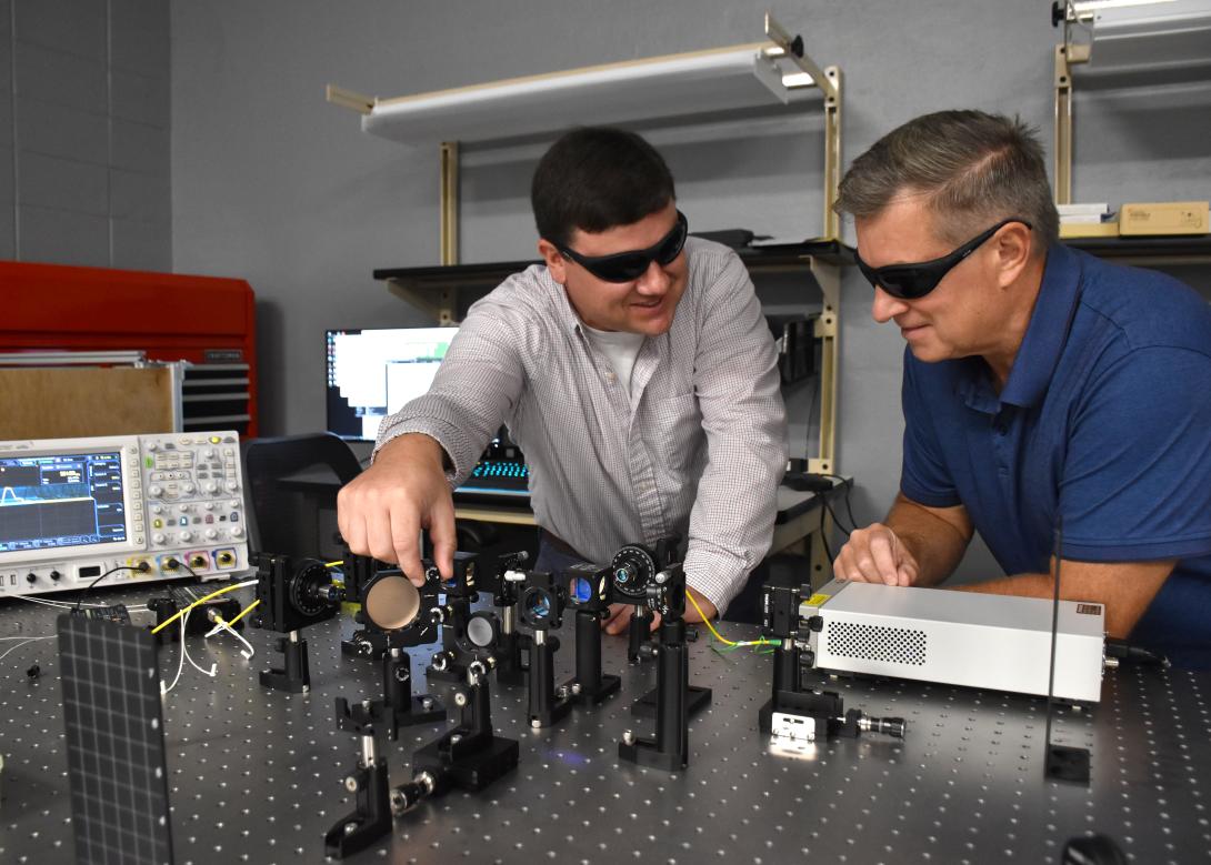 Members of the Technical Center quantum research team, review a quantum entanglement setup. Credit: Ronald Bailey, U.S. Army.