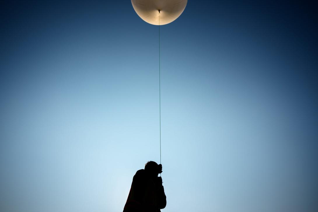 Summer Czarnowski, a geosciences intern at Sandia National Laboratories, holds a line tethered between a scientific payload and a weather balloon prior to launch at Moriarty Airport in New Mexico in July. Credit: Craig Fritz