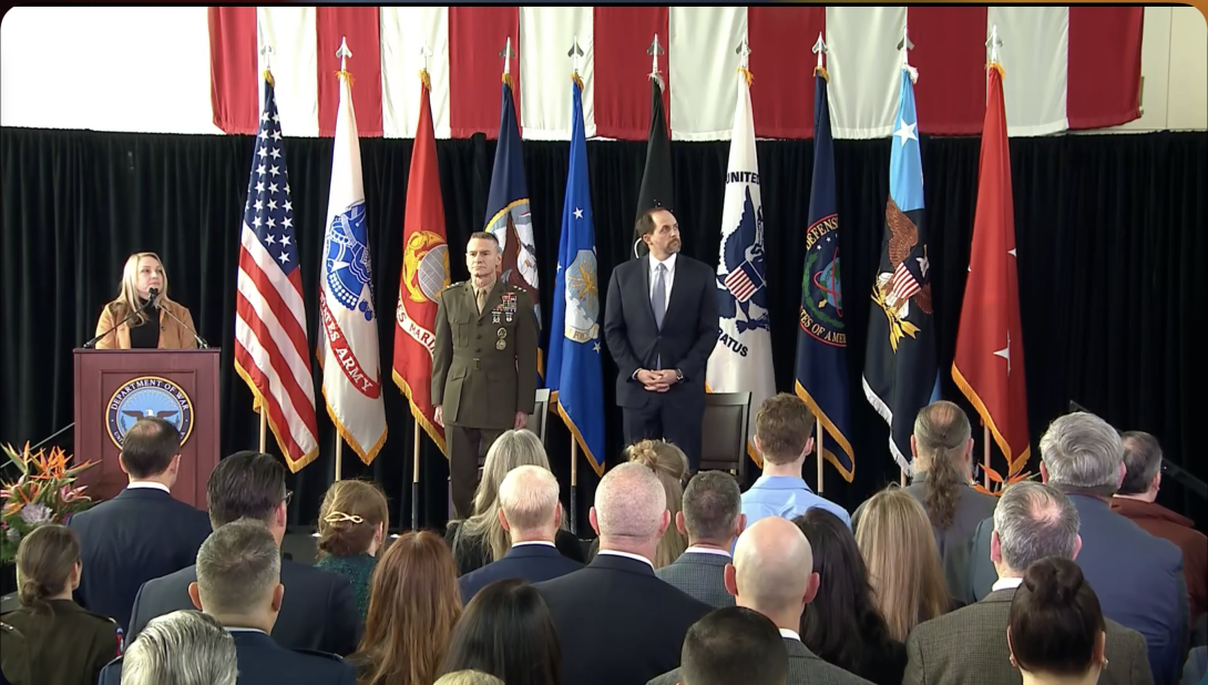 A defense official begins the ceremony for Lt. Gen. James Adams, USMC, (c) to become the director of the Defense Intelligence Agency, with Bradley Hansen, the undersecretary for Intelligence and Security, laying out the department's priorities for the agency.