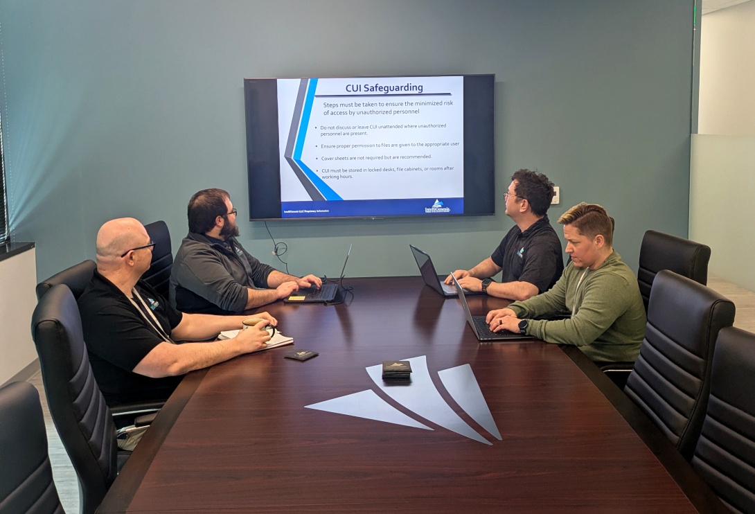 Members of IntelliGenesis' Cybersecurity Maturity Model Certification (CMMC) team discuss the process of meeting the CMMC requirements. Credit: IntelliGenesis photo by Laura Hildebrand