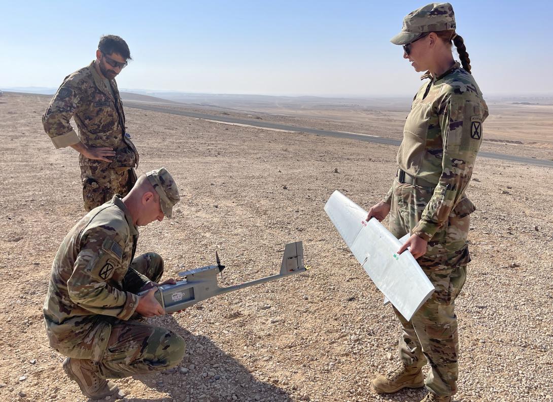 U.S. Army Sgt. 1st Class Jay Utter (kneeling), HHC 1-163rd Combined Arms Battalion, repairs an unmanned aerial vehicle (UAV) with Italian Air Force Warrant Officer Paolo Robles, commander of a counter-UAV team with the 16th Force Protection Wing of the Italian Air Force, and U.S. Army Capt. Olivia Cobiskey, as part of Exercise Eager Lion 22, in September 2022.  U.S. Army photo by Cpt. Olivia Cobiskey
