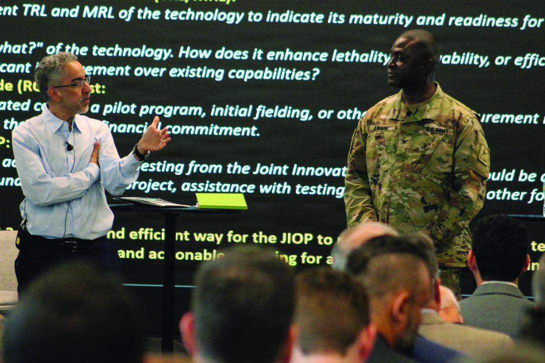 The U.S. Army Capability Program Executive Simulation, Training, Test and Threat’s chief technology officer, Marwane Bahbaz (l), speaks to Col. Peter Amara, assistant director to the deputy assistant secretary of the Army for Data, Engineering and Software and industry representatives during a Technical Exchange/Industry Day on March 10, 2026, at the Central Florida Tech Grove in Orlando, Florida. At the exchange, leaders from the Joint Innovation Outpost (JIOP) briefed attendees on key technology gap areas