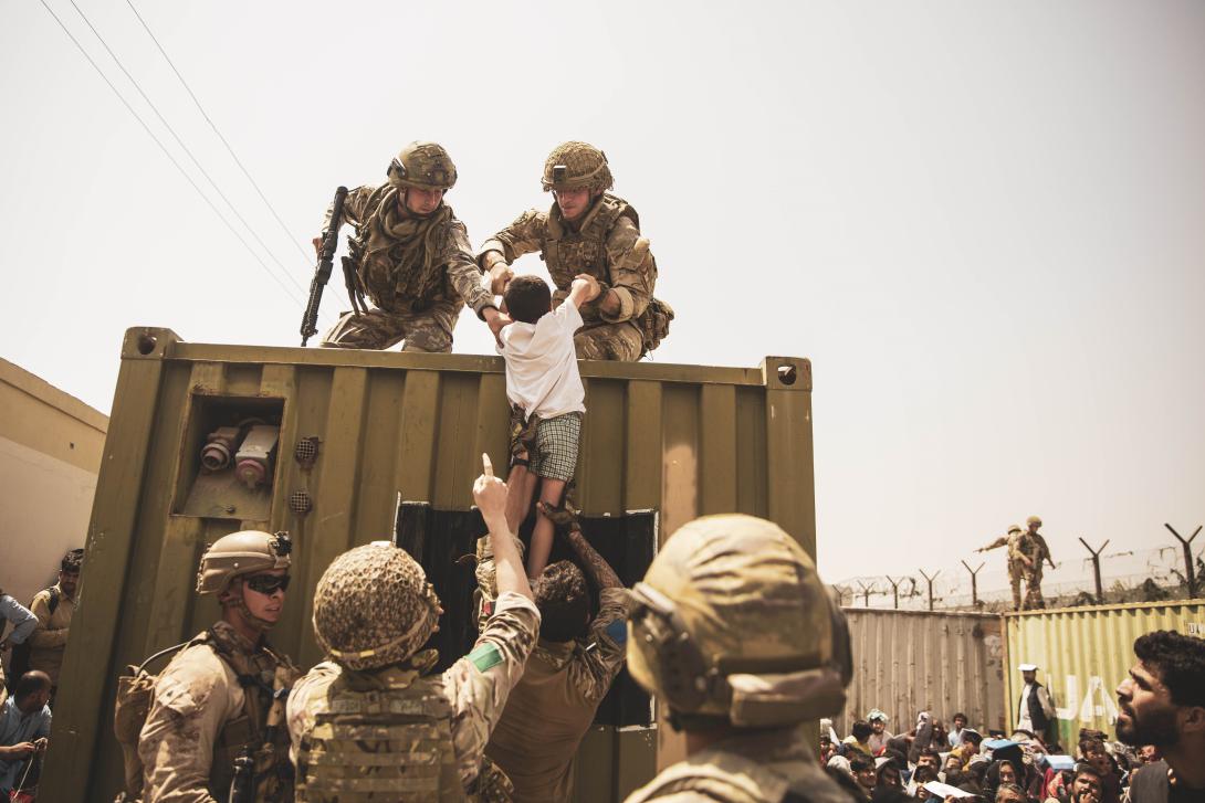 U.S. Marines, along with British and Turkish forces, assist a child during an evacuation at Hamid Karzai International Airport, Kabul, Afghanistan, August 2021. The non-combatant evacuation was the largest operation of its kind, and the data-related lessons learned will likely influence the full array of future military operations.  Marine Corps Staff Sgt. Victor Mancilla