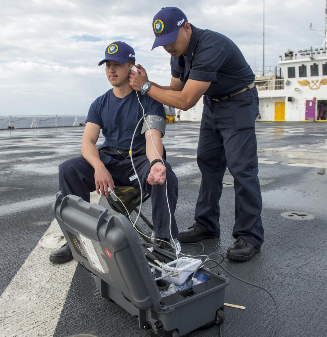 Lt. Cmdr. Art Ambrosio, USN (r), performs an ear examination on Hospital Corpsman 3rd Class Francis Soucie, USN, during the first trial run of a portable telemedicine unit on the flight deck of the U.S. Navy hospital ship USNS Mercy in 2018. This spring, the Mercy served on the U.S. West Coast to provide medical assistance during the COVID-19 pandemic.