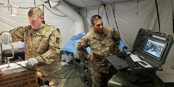 Maj. Ian Cassaday, USA (l), a surgeon with the 250th Forward Surgical Team, utilizes a Telehealth in a Bag kit and a GlobalMed TES to simulate a craniotomy performed by a non-neurosurgeon during testing of virtual health capabilities in the field.  U.S. Army 