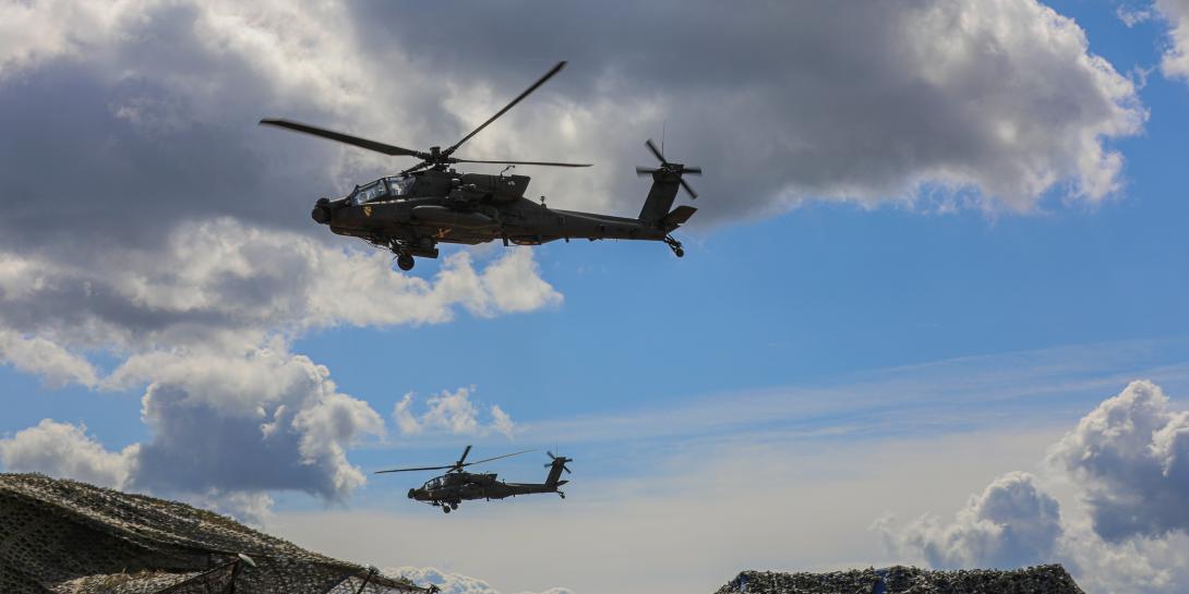 Two U.S. Army AH-64E Apache Guardian attack helicopters assigned to the 1st Cavalry Division fly over an observation area during a multinational live-fire exercise as part of DEFENDER-Europe 22 at Mielno Range in Drawsko Pomorskie, Poland on May 27. Manufacturer Elbit Systems of America is offering a new dual eye visor helmet system for helicopter pilots that incorporates multiple layers of real-time and historical data from multiple sensors. Credit: Department of Defense