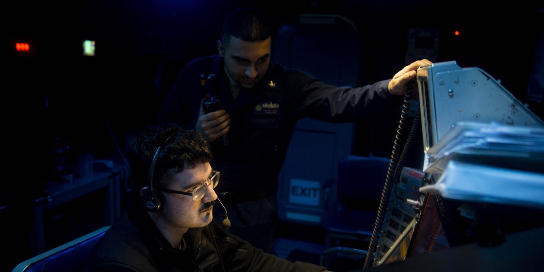 Two U.S. Navy operations specialists stand watch aboard the USS Dwight D. Eisenhower. The Navy must provide cybersecurity for major systems aboard ships as well as for smaller logistical systems, all of which are targets for digital adversaries.  U.S. Navy photo