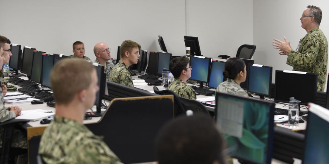 Rear Adm. Timothy White, USN, commander, Cyber National Mission Force, U.S. Cyber Command, shares feedback with students attending the Joint Cyber Analysis course at the Information Warfare Training Command (IWTC), Corry Station, Pensacola, Florida. The Unified Platform will assist members of all services in securing networks by enabling cyber warriors to prosecute full-spectrum cyberspace operations. Credit: Glenn Sircy/Center for Information Warfare Training Public Affairs