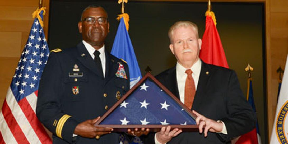 Maj. Gen. Cedric Wins, USA, commander of U.S. Army Research, Development and Engineering Command, presents a flag to Henry Muller Jr., who has retired as director of the Communications-Electronics Research, Development and Engineering Center after a nearly 33-year federal career. Donald Reago Jr. is serving as acting director.