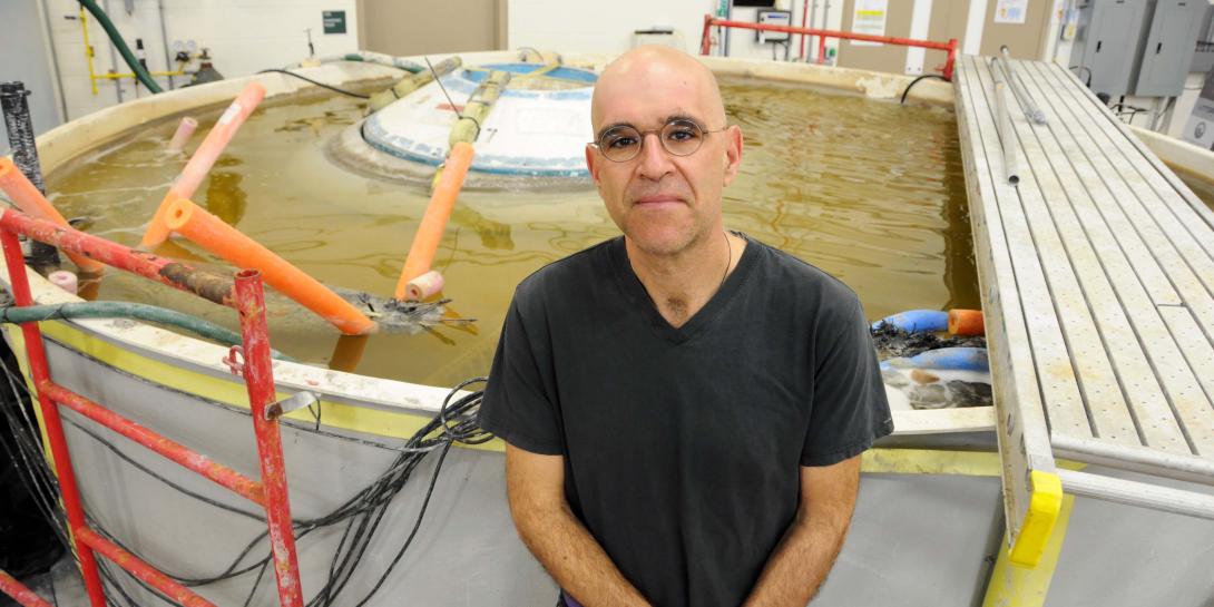  Lenny Tender, a research chemist at the Naval Research Laboratory, stands in front of a tank that mirrors marine environments at the Washington, D.C., facility. Partially submerged in the tank is a Hershey Kiss-shaped buoy that scientists use to develop the benthic microbial fuel cell, a persistent power supply for marine-deployed applications.