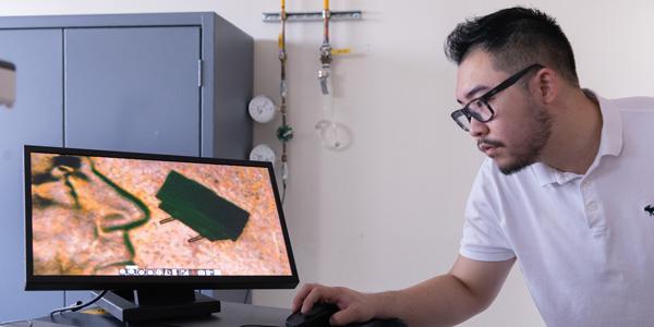 Georgia Tech graduate student Zhijian (Chris) Hao is shown with a microscope image of a micro-bristle-bot on a U.S. penny. Credit: Allison Carter, Georgia Tech