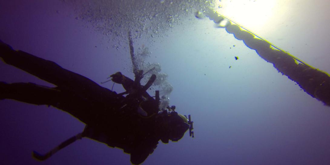 A diver descends along a deep water mooring buoy off of the coast of Guam to conduct inspection, maintenance and repair of various underwater assets.