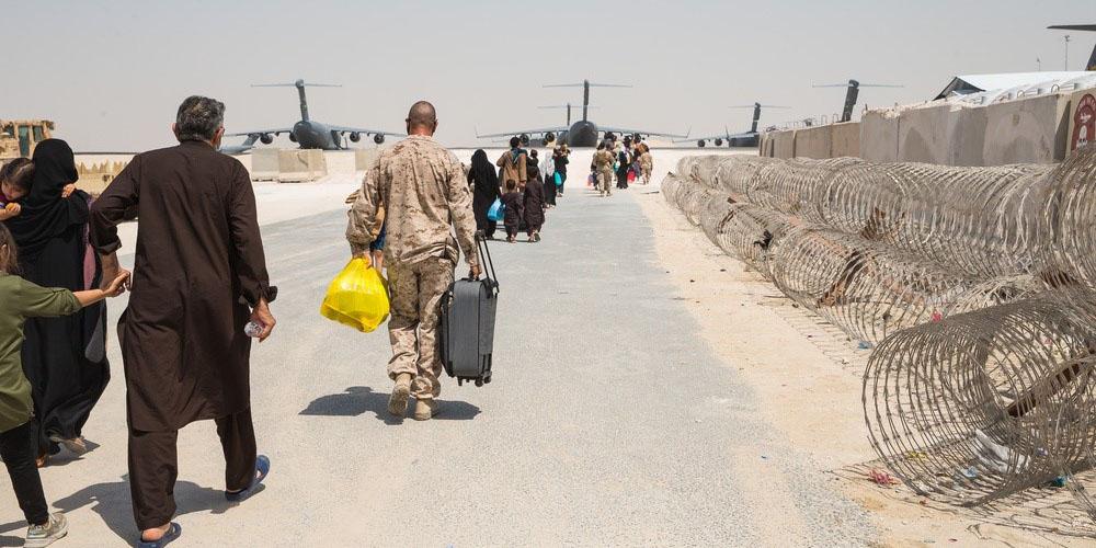 Master Sgt. Michael Lesterick, USMC, carries an Afghan evacuee’s luggage as they board a plane at Al Udeid Air Base, Qatar, September 1, 2021. The Department of Defense, including its combatant commands, such as the U.S. Transportation Command, is still supporting the evacuation of American citizens, special immigrant visa applicants and other at-risk individuals from Afghanistan. Credit: U.S. Marine Corps photo by Lance Cpl. Kyle Jia