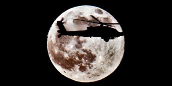 An AH-64D Apache attack helicopter departs the flightline under a full moon to conduct operations from Camp Taji, Iraq. Boeing has received a contract for an additional Longbow crew trainer.