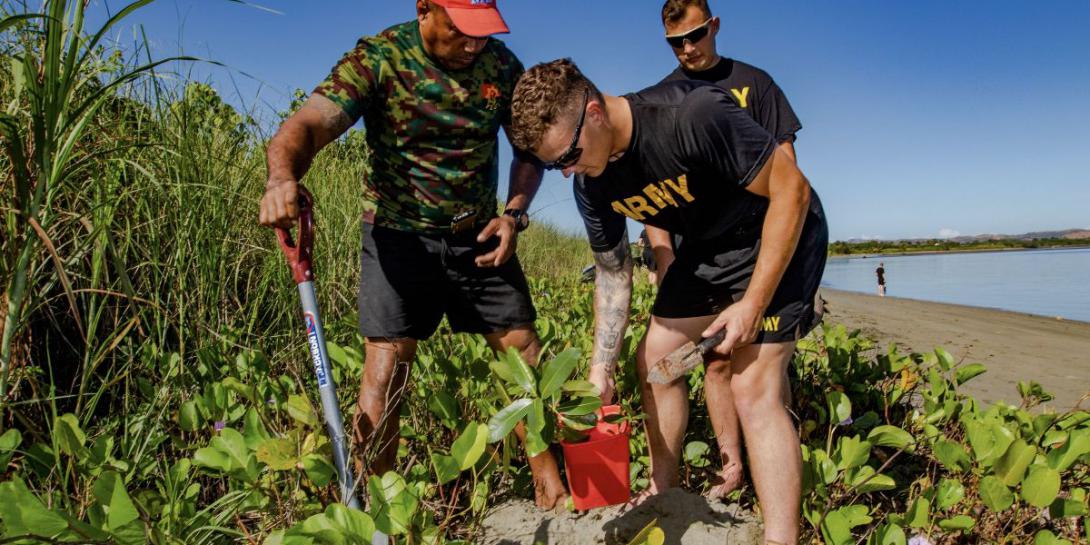 Two U.S. Army specialists join a Fijian Army sergeant in planting Dilo trees as part of a coastal and reef revitalization project in the Republic of Fiji. The U.S. Army works with local officials domestically and overseas in projects to support environmental concerns to avoid or repair damage.