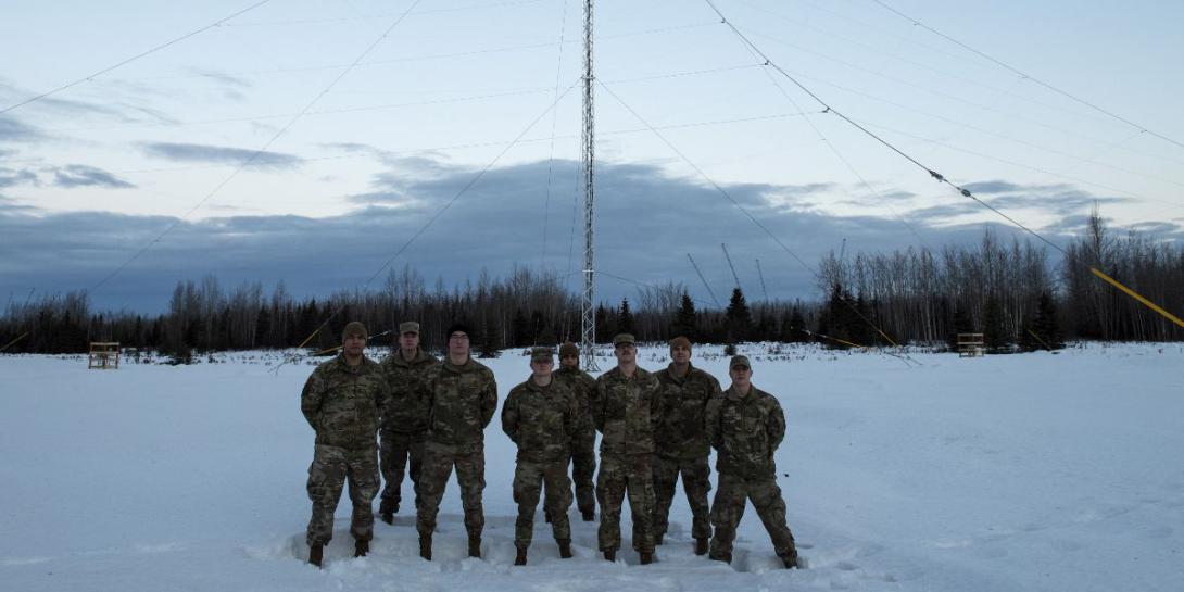 U.S. Air Force airmen stand in front of a 120-foot-tall HF Global Communications Systems (HFGCS) antenna tower at Joint Base Elmendorf-Richardson, Alaska. Slated for completion this year, the station is one of 13 strategically located around the world for HF communications among ground facilities and in-flight aircraft seaborne vessels and submarines. U.S. Air Force photo