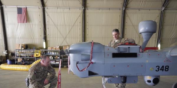 Two U.S. Navy officers inspect an MQ-5B Hunter unmanned aerial vehicle (UAV) at Kandahar Airfield in Afghanistan. The Navy’s increased use of UAVs is changing the nature of its air operations, but it also is raising concerns about manned versus unmanned missions.