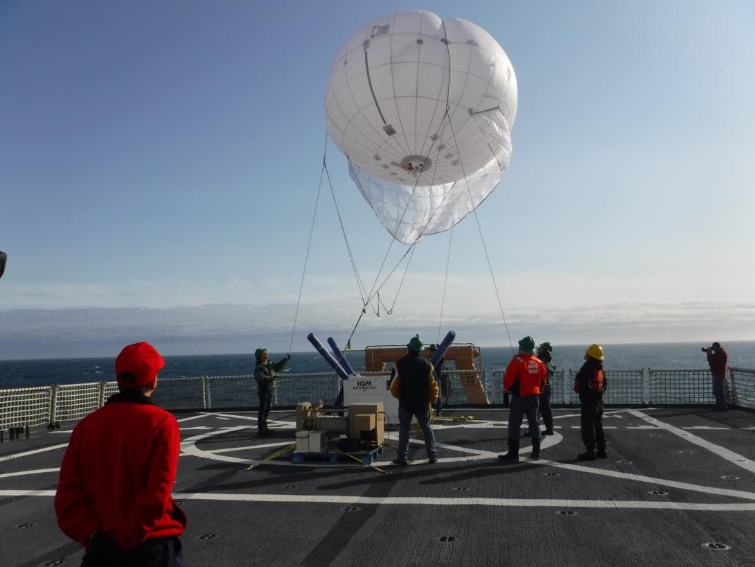 A Coast Guard test team begins deployment of an aerostat off the flight deck of the U.S. Coast Guard Cutter Healy in the Arctic region. This year, researchers are evaluating a smaller version with higher wind capabilities. The aerostat will carry a communications package that will allow contact with an unmanned aerial vehicle that has flown beyond the line of sight.