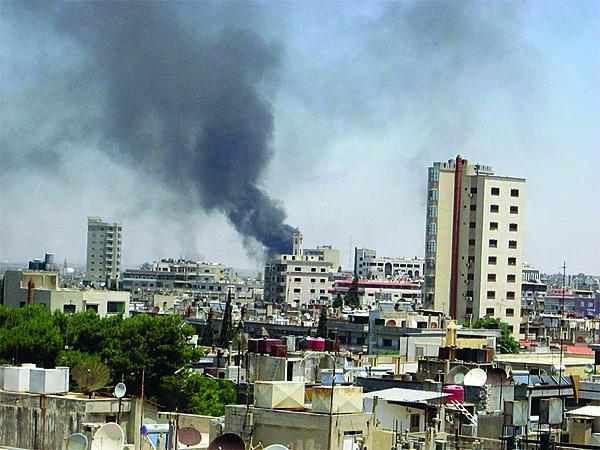 Smoke drifts into the sky from buildings and houses hit by shelling in Homs, Syria. Many Jihadi fighters leaving Syria will funnel through the Balkans and may pose a threat to other parts of the world.